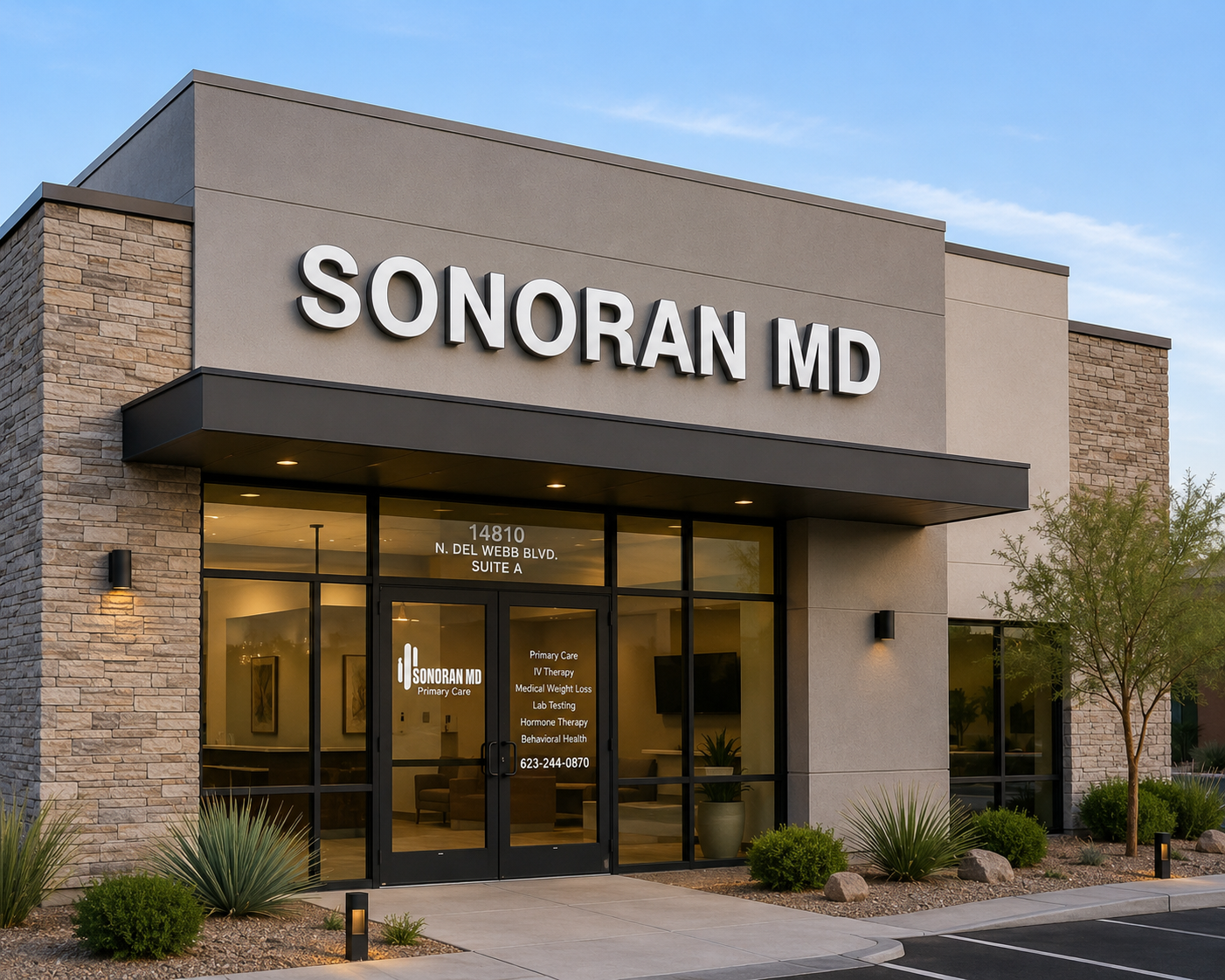 A front-facing view of a sleek, modern medical clinic building bathed in the warm glow of golden-hour light, featuring a clean stone and stucco facade with large glass windows and sharp architectural details. The noticeable "SONORAN MD" sign crowns the structure, while desert-friendly landscaping and an inviting interior with soft lighting peek through the glass, highlighting the professional services offered within.